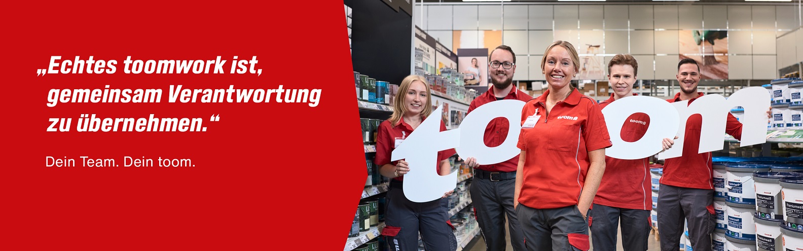 In einem Baumarkt stehen fünf Mitarbeitende und halten die Buchstaben des Wortes toom in den Händen