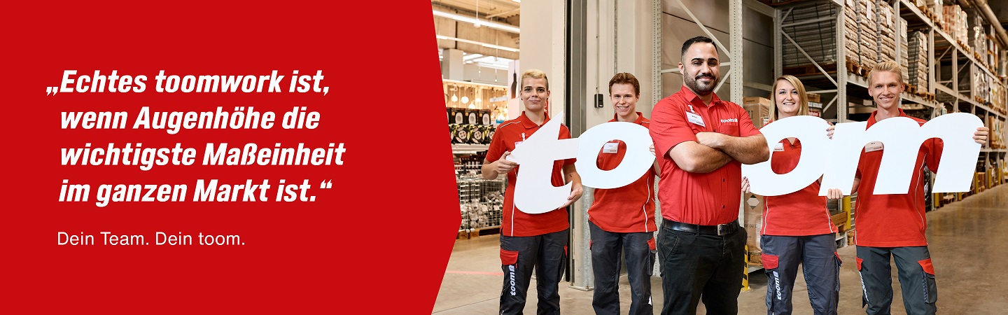In einer Logistikhalle stehen fünf Mitarbeitende und halten die Buchstaben des Wortes toom in den Händen