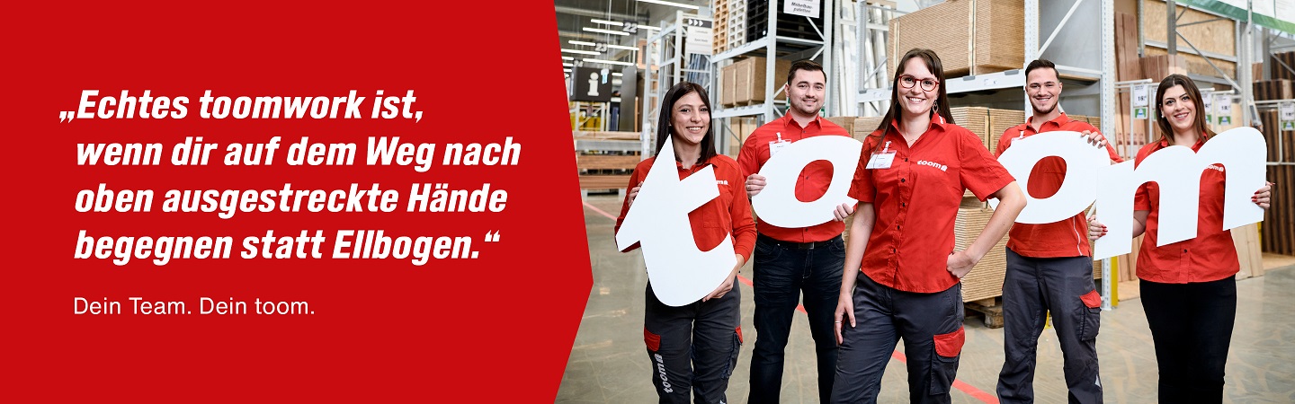 In einem Baumarkt stehen fünf Mitarbeitende und halten die Buchstaben des Wortes toom in den Händen